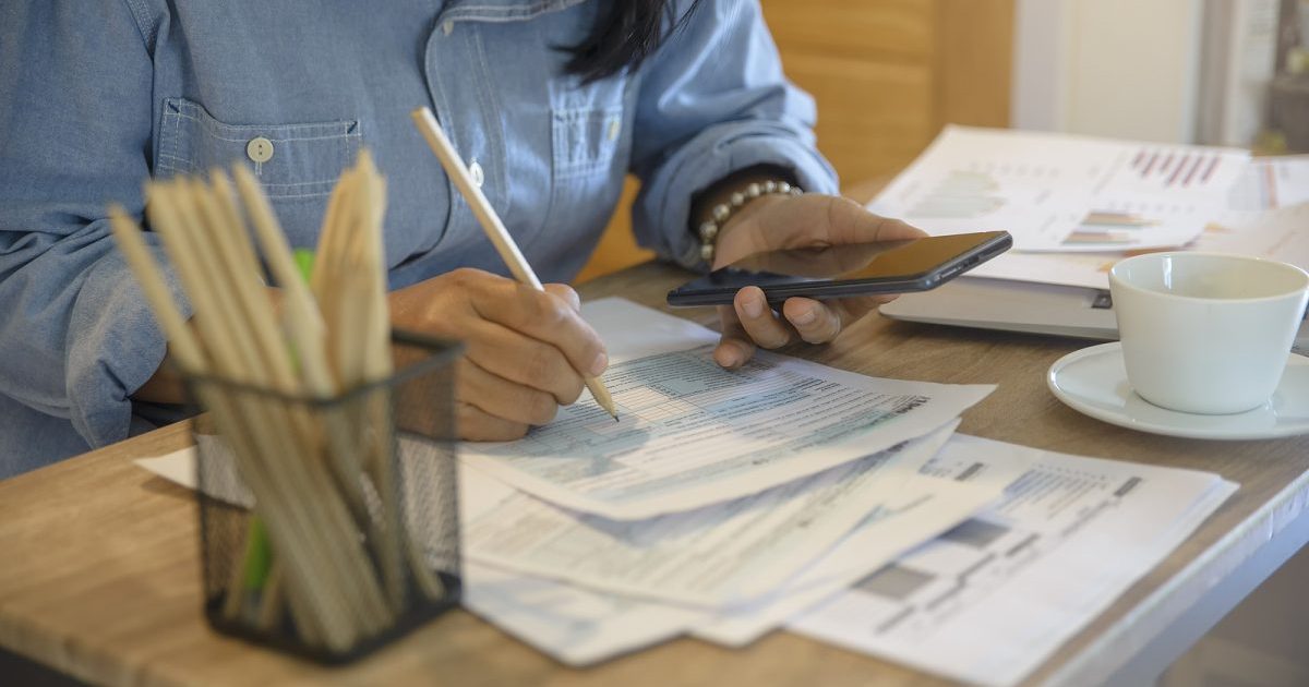 person hunched over papers with calculator in hand